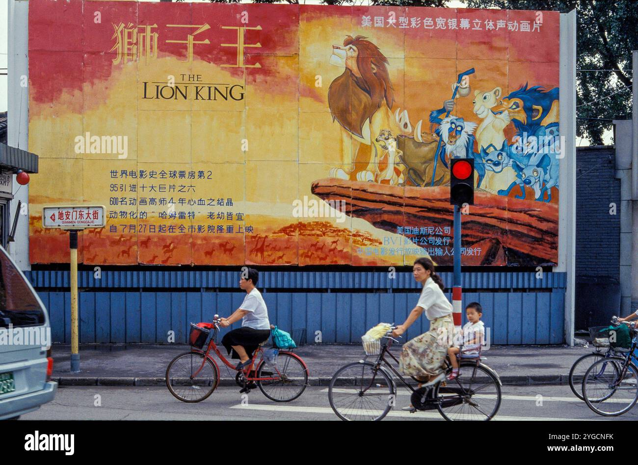 Chine, Shanghai , cyclistes passant une affiche de film Walt Disney. Banque D'Images