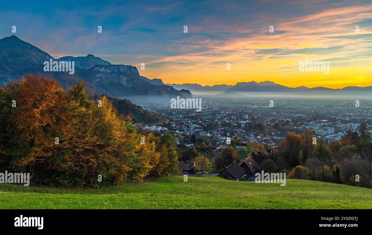 Panorama coucher de soleil dans la vallée du Rhin, avec rémanence, ciel bleu sur la ville de Dornbirn, prairie et champs. arbres colorés d'automne. belle récréation Banque D'Images