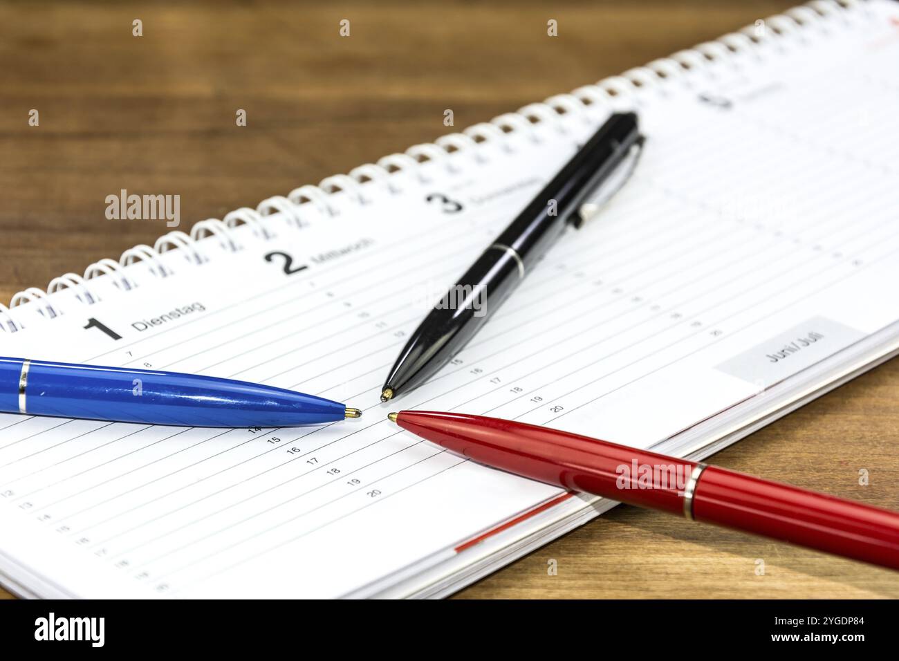 Stylos posés sur un horaire et poting vers une date et une heure spécifiques (avec légendes des jours de la semaine en allemand) Banque D'Images