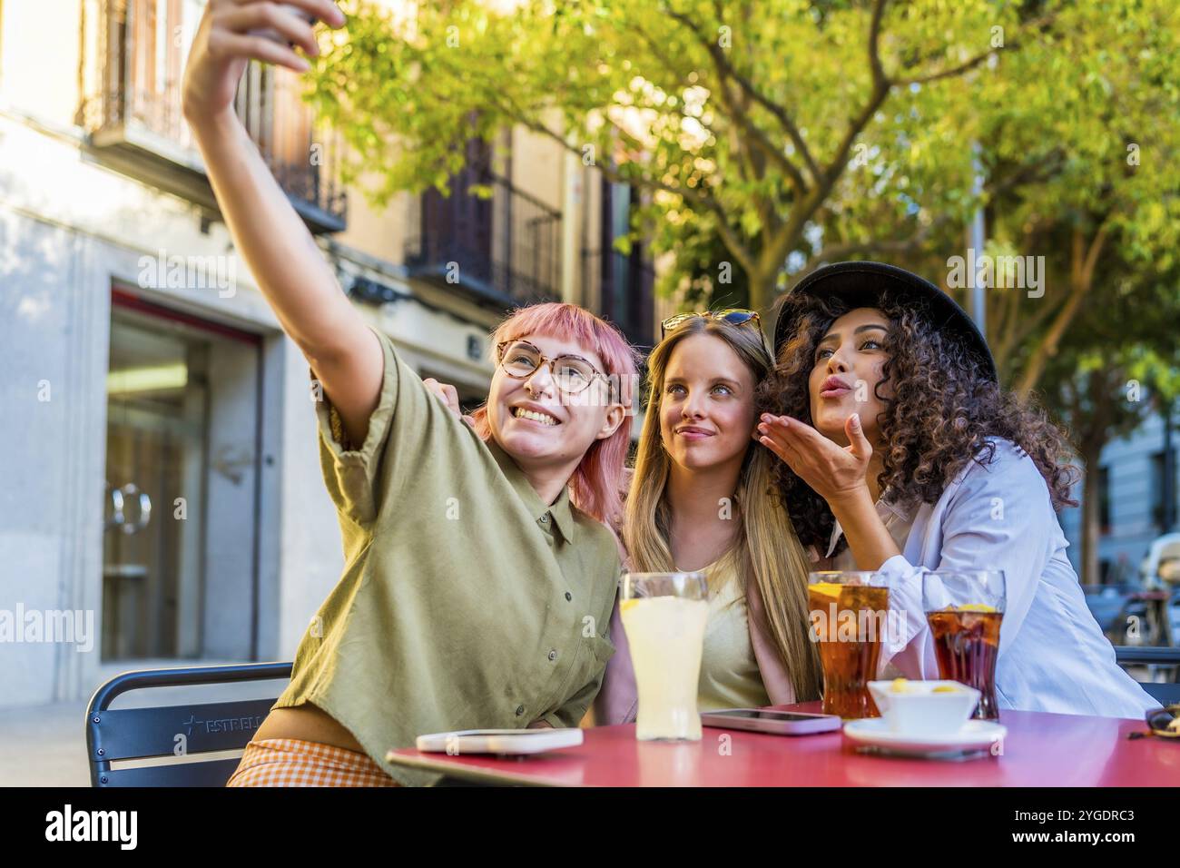 Diverses femmes latines et caucasiennes modernes s'embrassent tout en prenant selfie sur une terrasse extérieure Banque D'Images