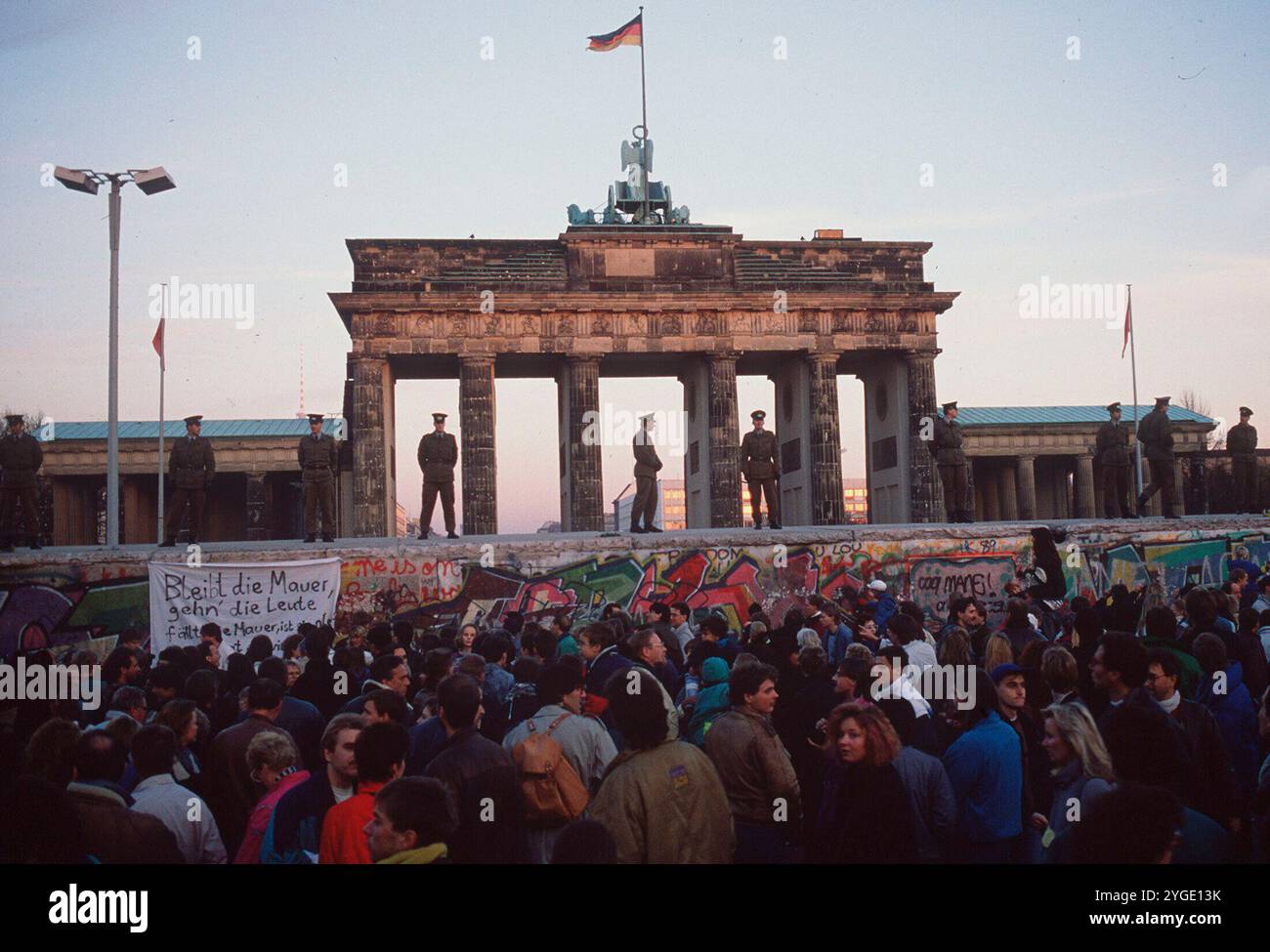 ARCHIVE PHOTO : il y a 35 ans, le 9 novembre 1989, le mur de Berlin est tombé. La porte de Brandebourg avec le 'mur' au premier plan. Les policiers du peuple sont debout sur le mur, et en dessous d'eux beaucoup de gens se tiennent devant le mur ; format paysage. ? Banque D'Images