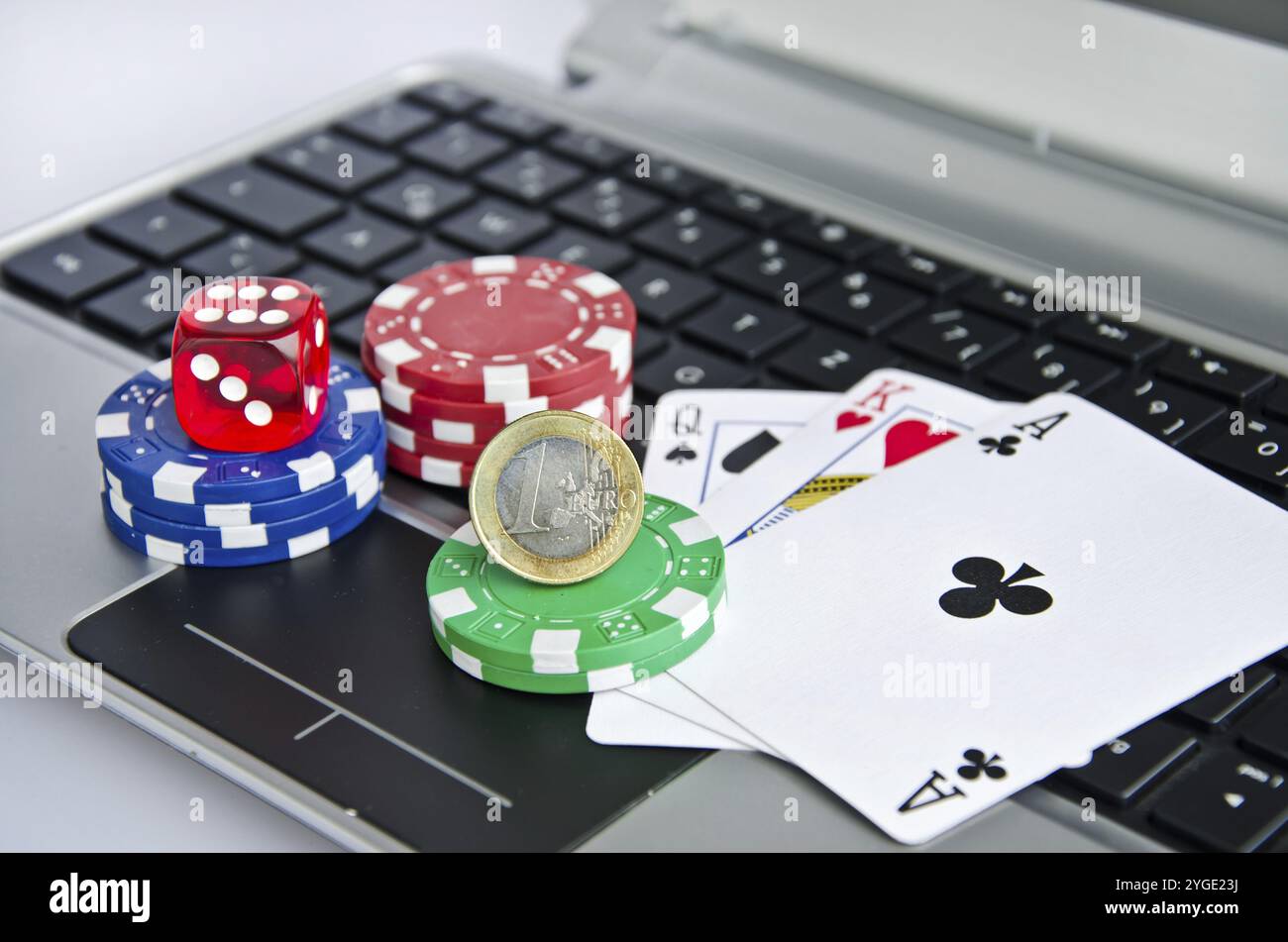 Jouer aux cartes, jetons de casino et pièce d'euro sur un clavier d'ordinateur portable symbolisant le jeu en ligne Banque D'Images