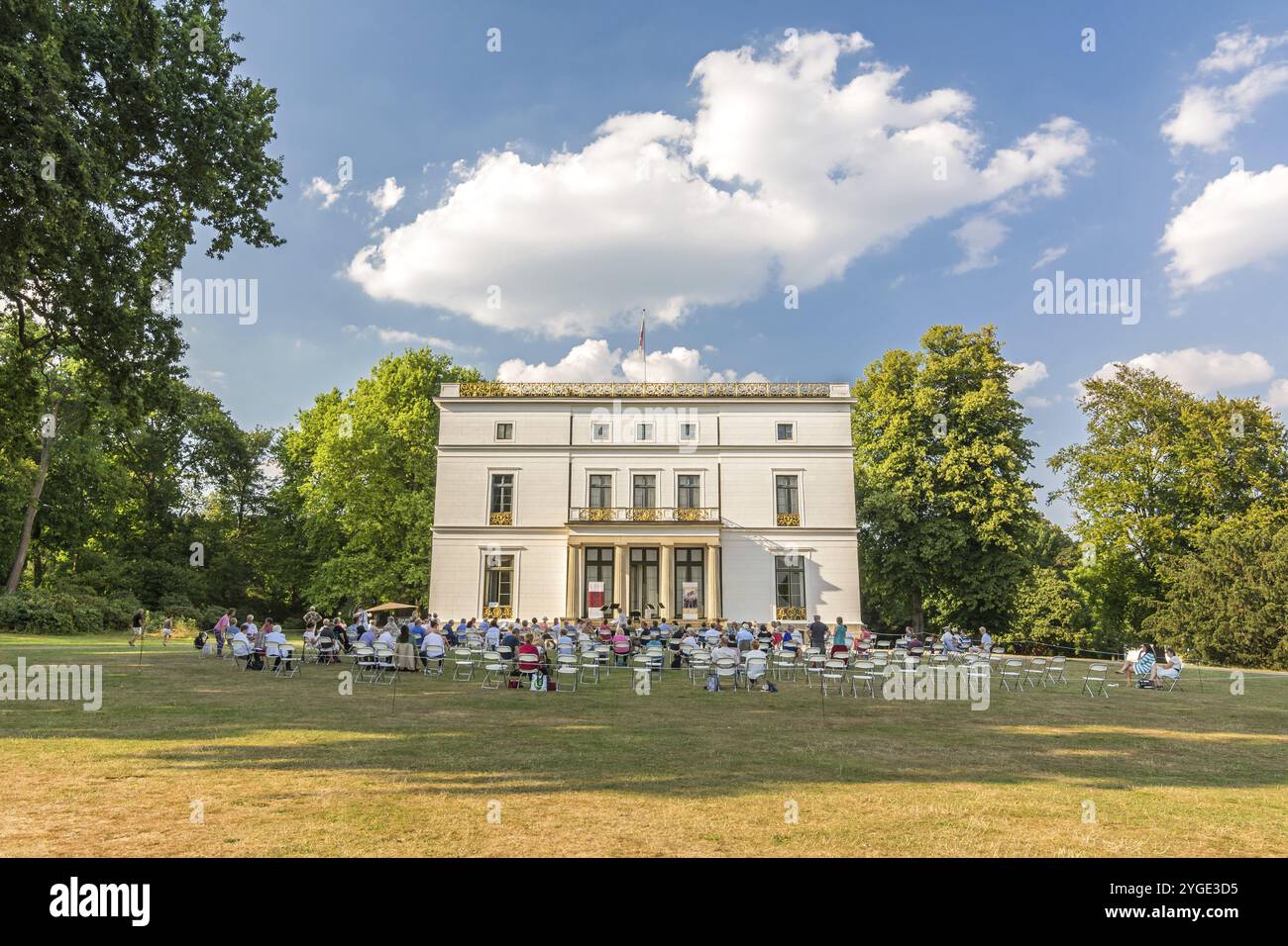 Auditoire d'un concert en plein air dans un parc (Jenischpark à Hambourg, Allemagne) devant une belle demeure blanche en été Banque D'Images