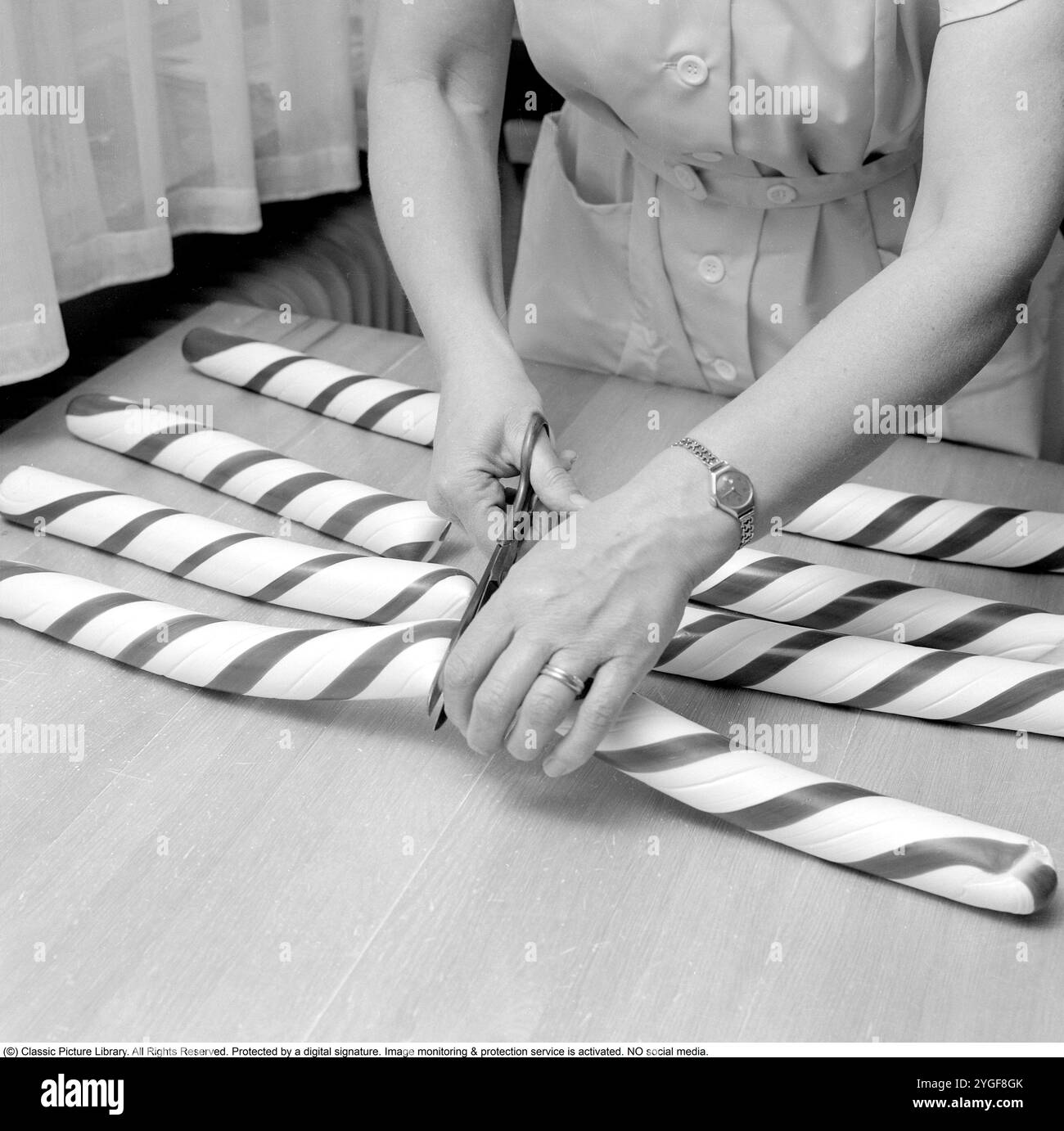 Polkagris (pluriel : polkagrisar) est un bonbon suédois inventé en 1859 par Amalia Eriksson dans la ville de Gränna, en Suède. Il reste un bonbon bien connu bien que vieux-mode en Suède, souvent vendu dans les foires, les marchés de Noël, etc. Il est encore étroitement associé à Gränna. Le bâton de bonbon traditionnel polkagris est blanc et rouge, et est aromatisé à la menthe poivrée. Le nom « polkagris » signifie littéralement « cochon à polka ». Le bonbon est fait de pâte à sucre qui est bouillie, pétrie sur une table de cuisson en marbre, tirée et tordue à la main à la bonne taille. Margita Mathias est vue faire des polkagri Banque D'Images