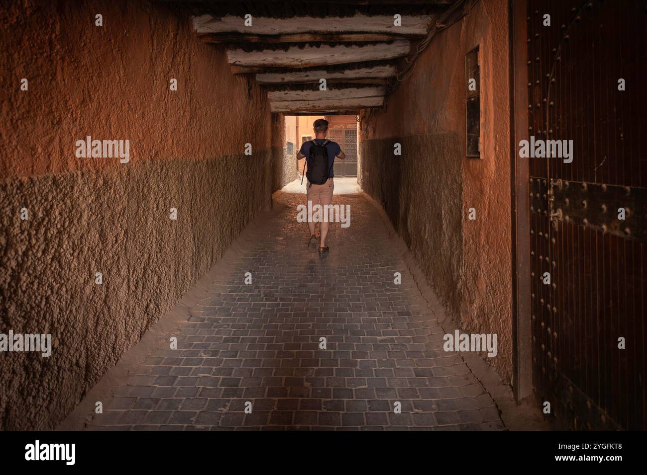 Un touriste masculin marchant dans une rue étroite dans la vieille médina, murs de charme rustique dans la ruelle du tunnel, voyageur en solo explorant Marrakech, Maroc Banque D'Images