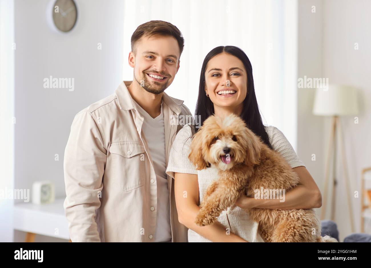 Portrait de couple de famille heureux tenant chien ensemble à la maison Banque D'Images