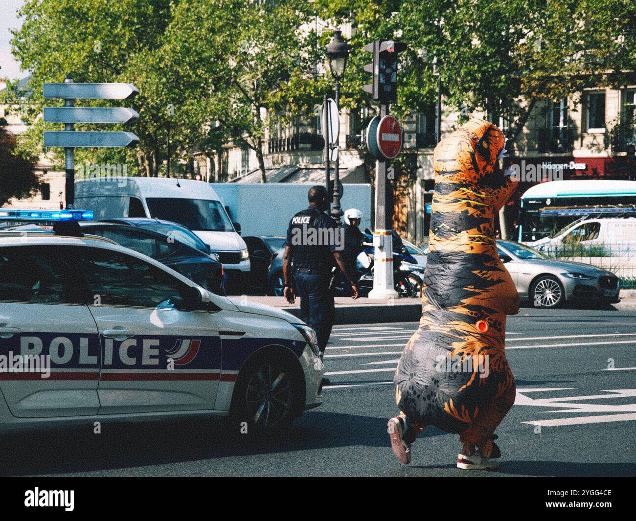 Une manifestation à Paris avec une présence policière et un manifestant en costume T-Rex, mêlant humour et activisme dans une déclaration politique unique. Banque D'Images