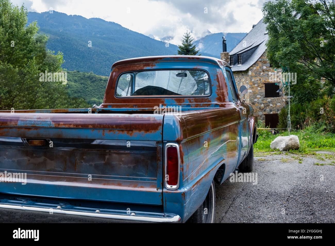 Une camionnette américaine originale à essence entièrement restaurée avec de la rouille vernie est garée dans le jardin d'une maison de campagne en pierre avec un noir Banque D'Images