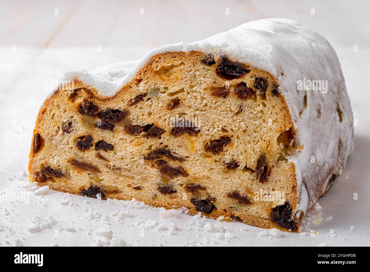 Pain en forme de gâteau Stollen coupé en deux gros plan. Pain de Noël allemand traditionnel de fruits secs, noix et épices enrobés de sucre en poudre sur une table. Banque D'Images