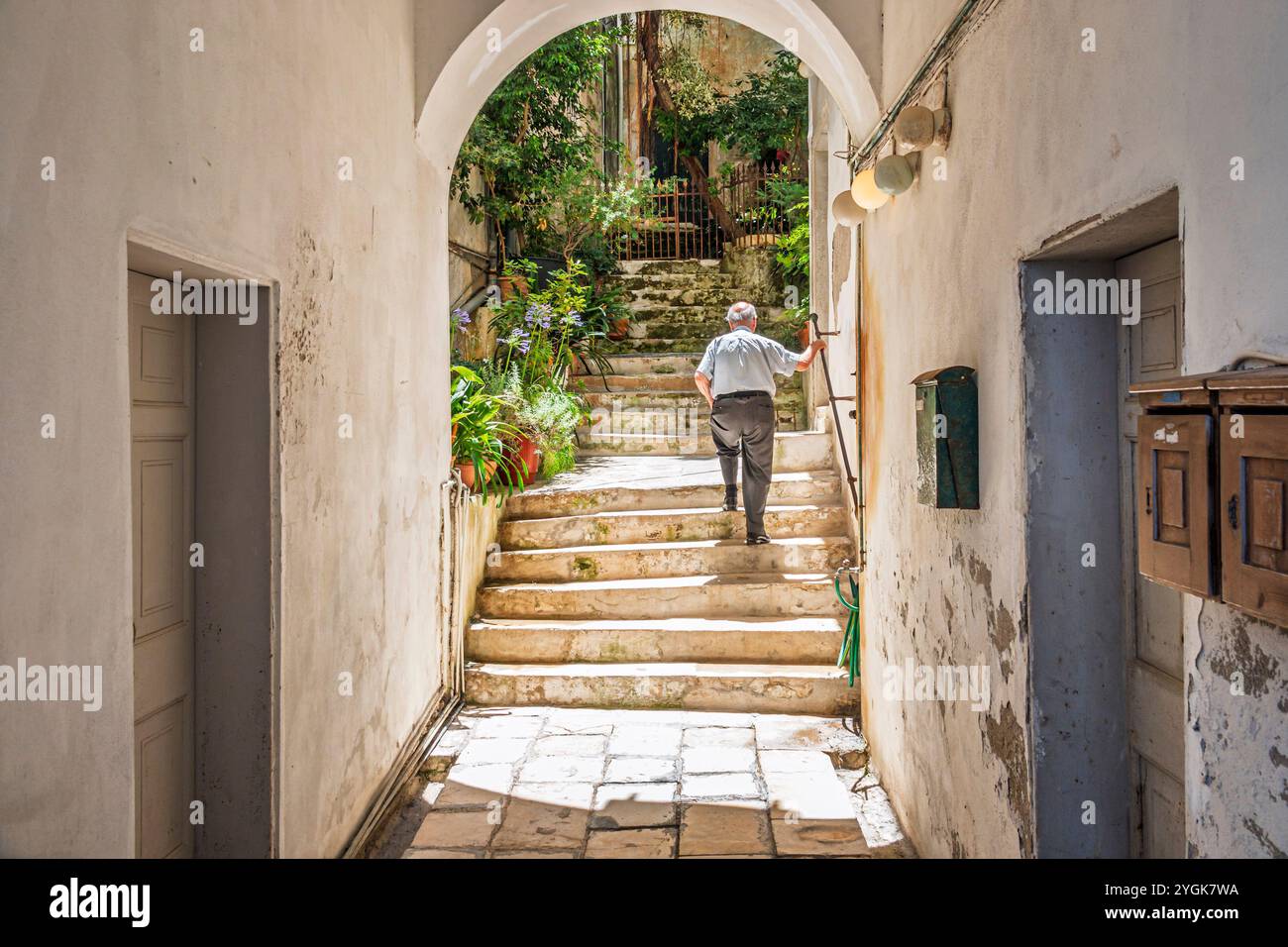 Corfou Grèce, vieille ville Kerkyra Palaio poli, près de la rue Arseniou, homme senior masculin, entrant dans la cour du bâtiment résidentiel, boîte aux lettres résidente Banque D'Images