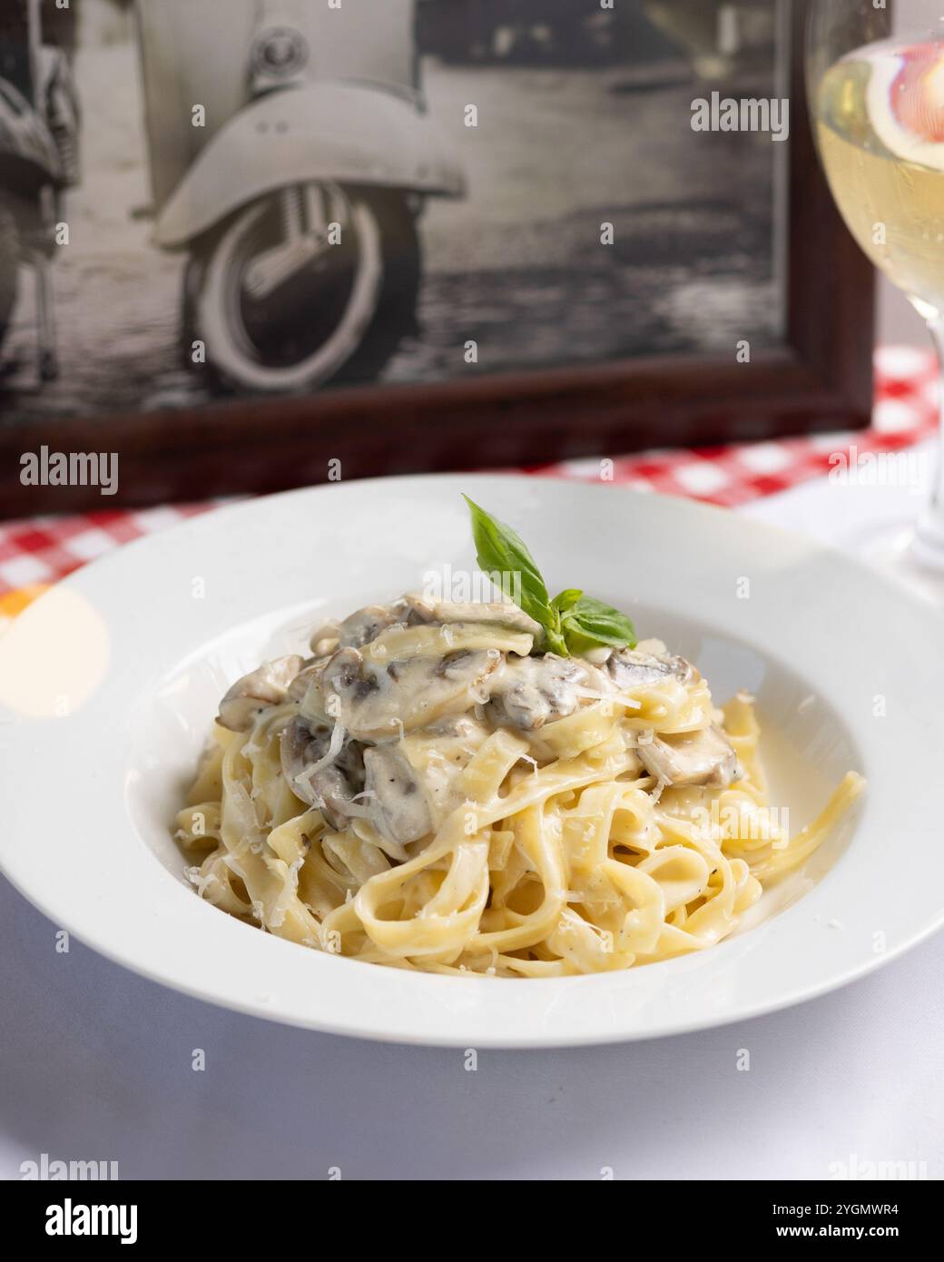 Pâtes au talian avec sauce blanche crémeuse, garnies d'herbes fraîches dans un cadre rustique de restaurant Banque D'Images