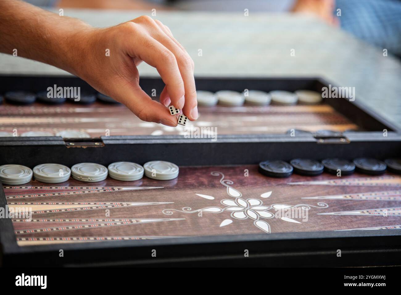 Lancer des dés à la main dans un gros plan de jeu de backgammon traditionnel Banque D'Images