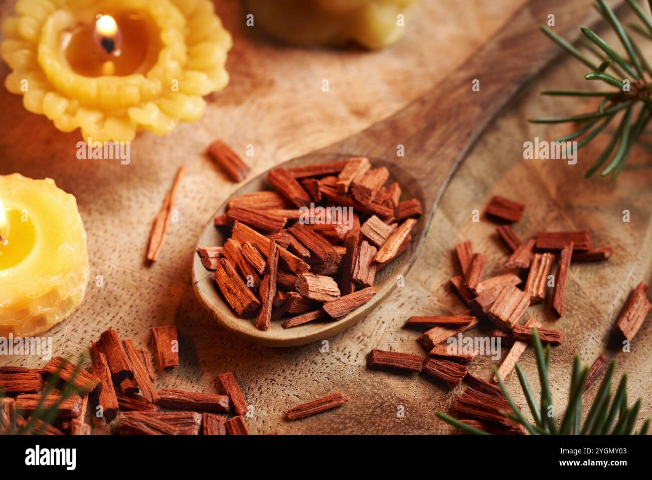 Copeaux de bois de santal rouge sur une cuillère en bois avec des bougies de cire d'abeille et des branches d'épicéa Banque D'Images