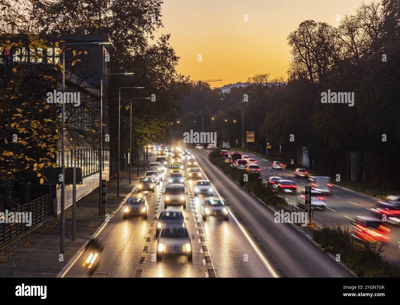Rue du centre-ville avec circulation intense le soir. Traînées de lumière dynamiques avec temps d'exposition long. Coucher de soleil. Route fédérale à six voies au Neckartor In Banque D'Images