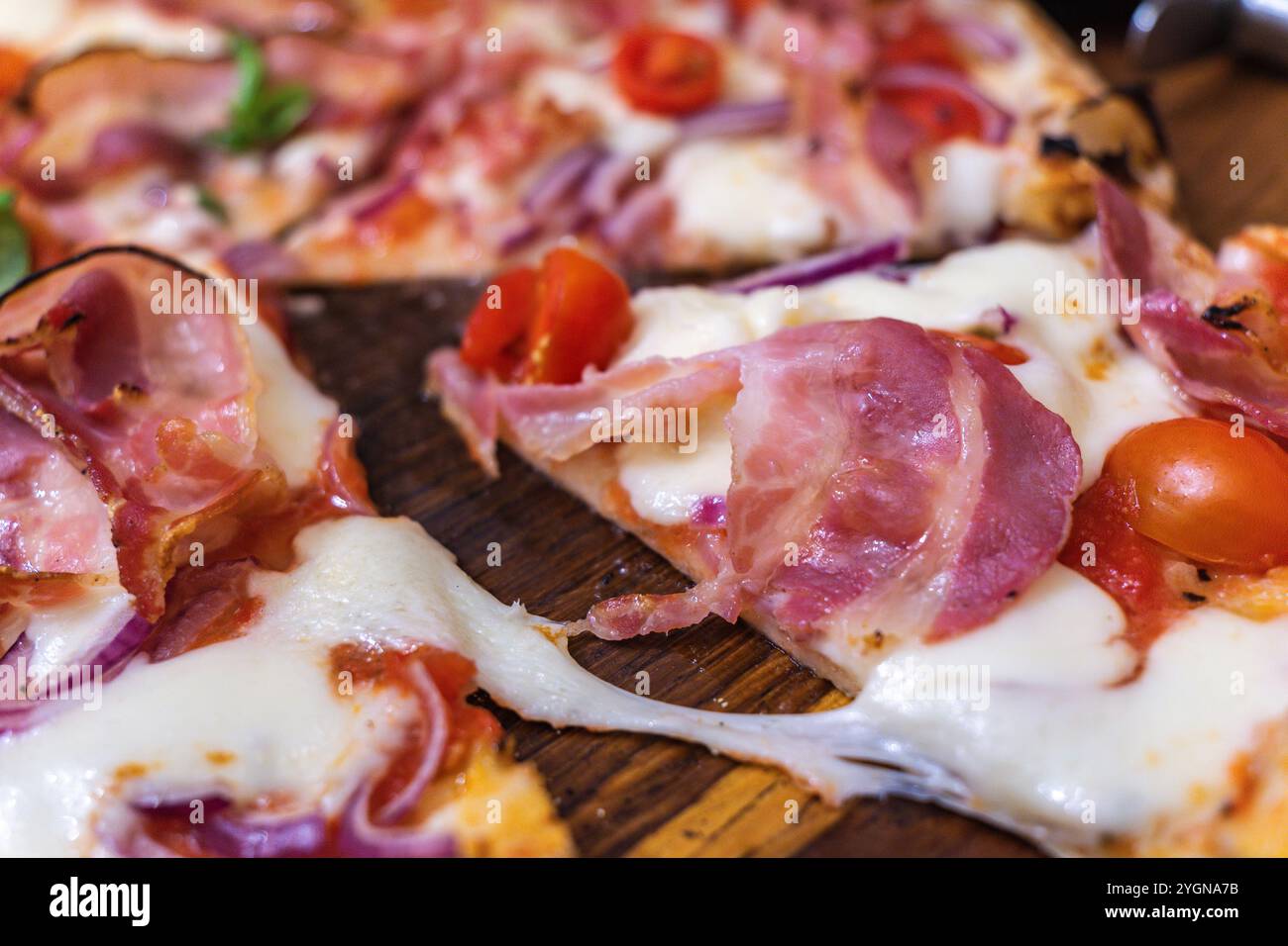 Délicieuse pizza Prosciutto garnie de tomates fraîches et de mozzarella dans un cadre de restaurant confortable Banque D'Images