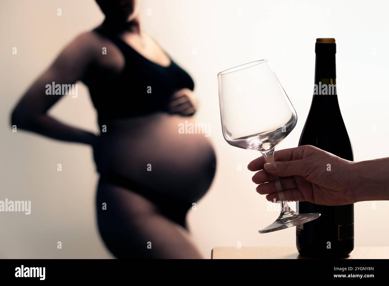 Alcool et femme enceinte. Grossesse et vin. Verre à la main et bouteille. Mauvais pour la fertilité et la santé. Danger du syndrome foetal. Bébé et jeune mère. Banque D'Images