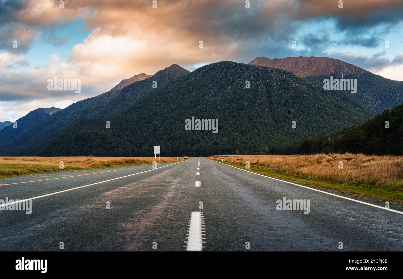 Milford Road en direction de la montagne parmi les prairies dans la soirée au parc national de Fiordland, Nouvelle-Zélande Banque D'Images