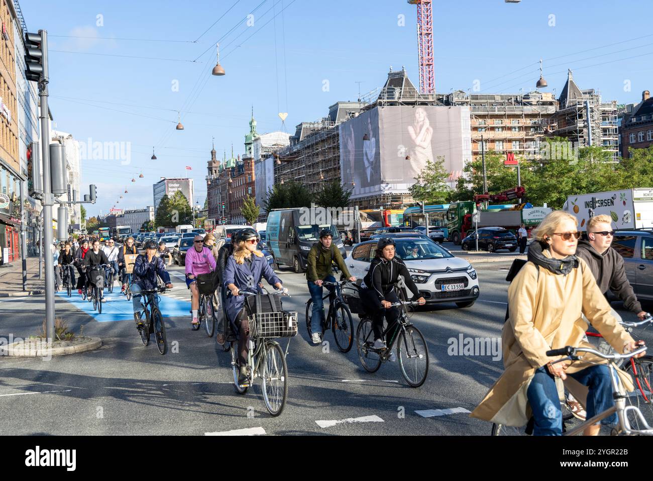 Des hommes et des femmes circulant à vélo dans le centre-ville de Copenhague dans une piste cyclable dédiée à côté des véhicules à moteur Banque D'Images