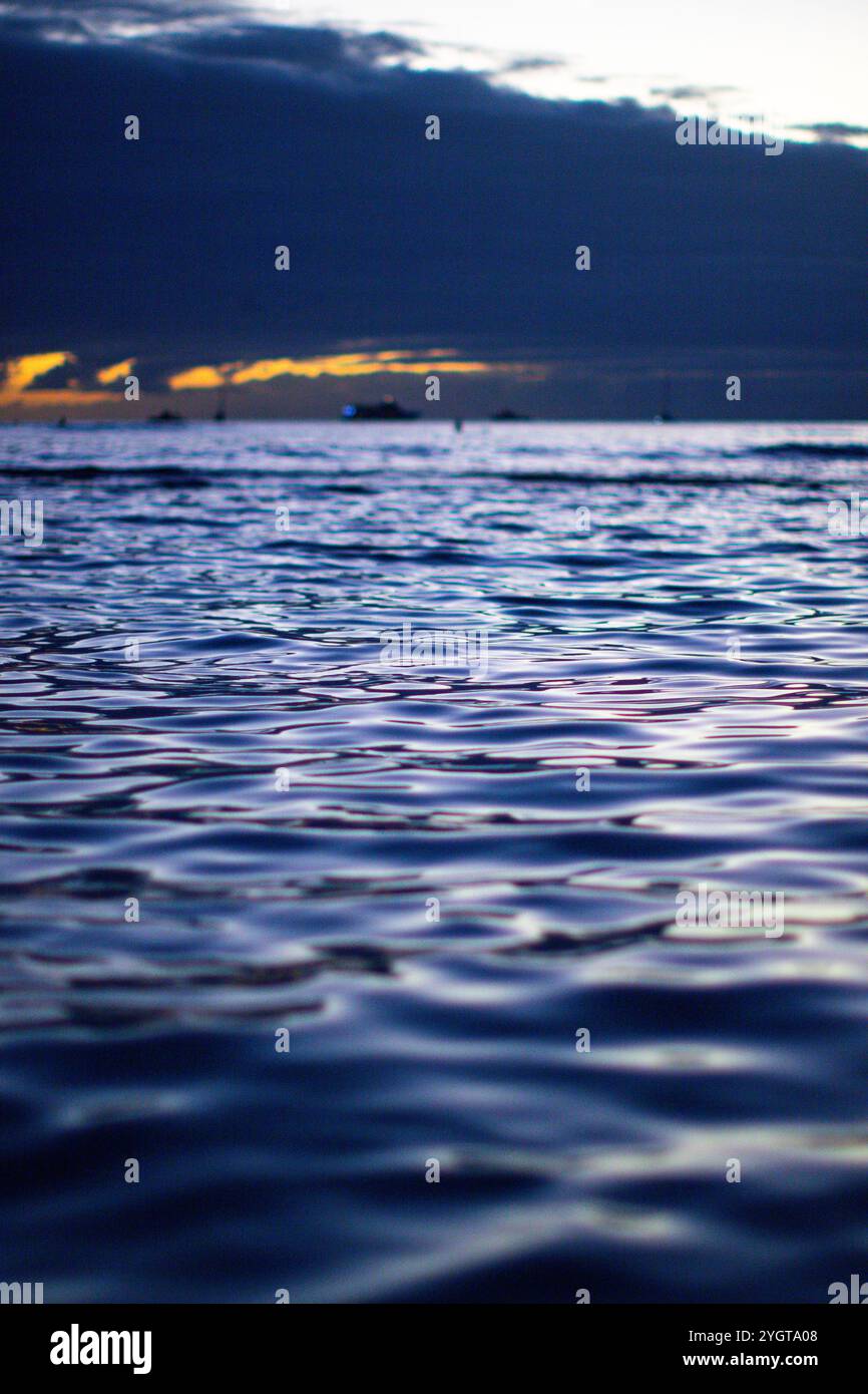 Les vagues du crépuscule se déplacent sous un ciel sombre, signalant la fin de la journée, Waikiki Banque D'Images