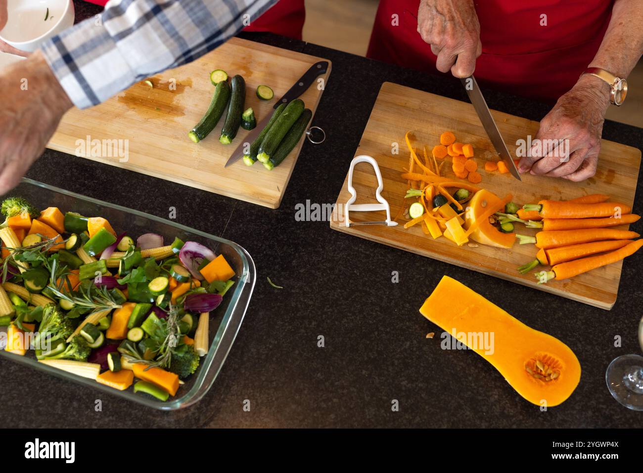 Couple senior préparant des légumes colorés pour un repas de vacances festif ensemble, à la maison Banque D'Images