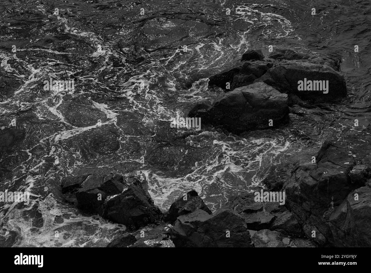 Prise de vue aérienne spectaculaire d'une côte accidentée. Fond d'écran naturel, avec des rochers côtiers et des vagues écrasantes. Image en noir et blanc Banque D'Images