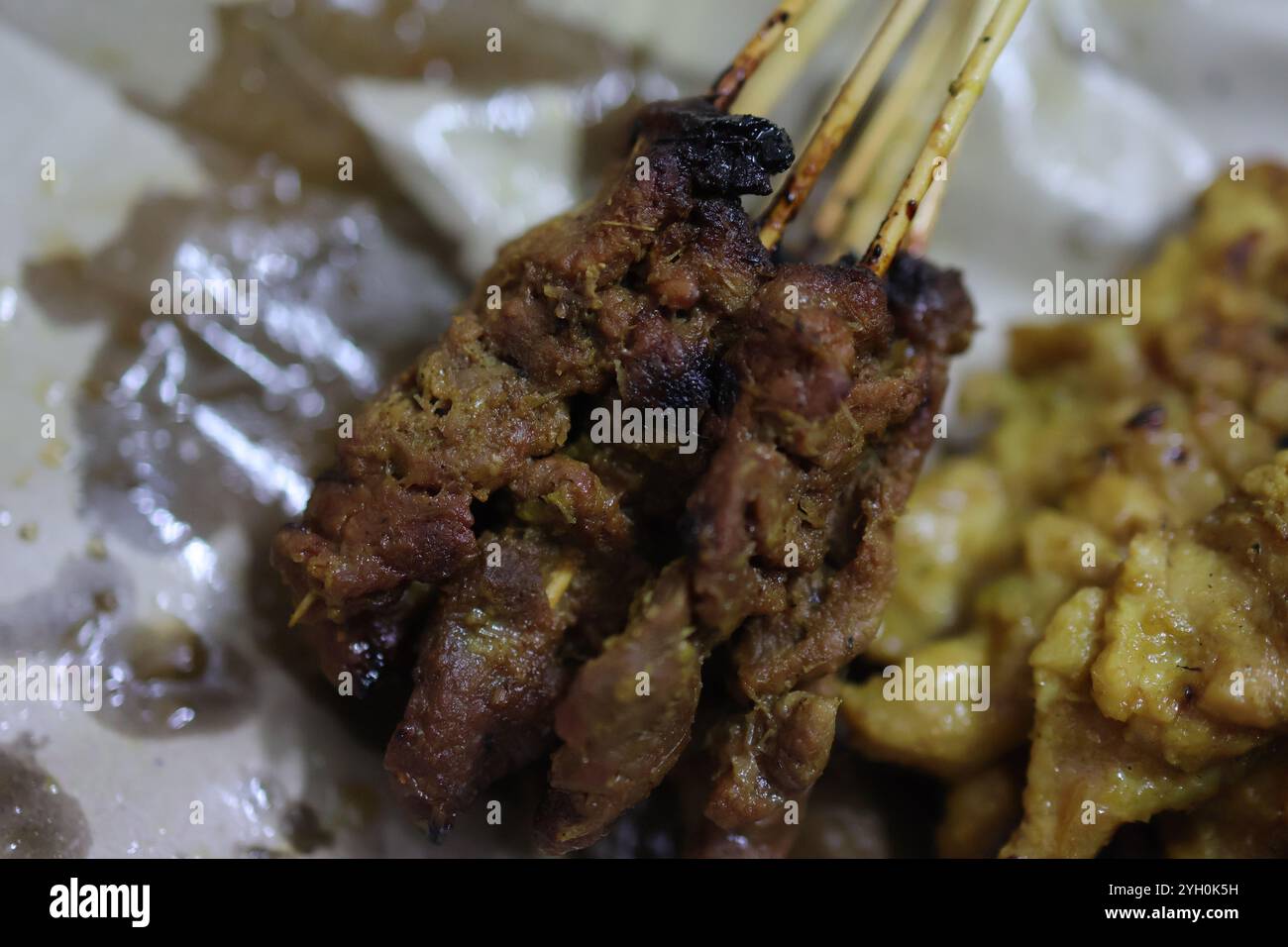 Un gros plan détaillé de succulentes brochettes de satay grillées aux bords carbonisés et à la marinade riche. Banque D'Images