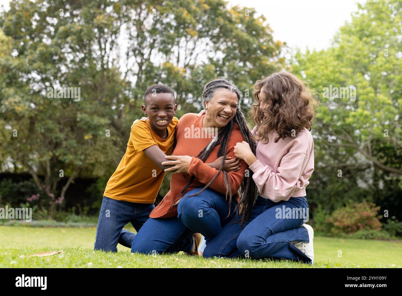 famille mutliraciale riant ensemble à l'extérieur, profitant d'un moment ludique sur l'herbe verte Banque D'Images