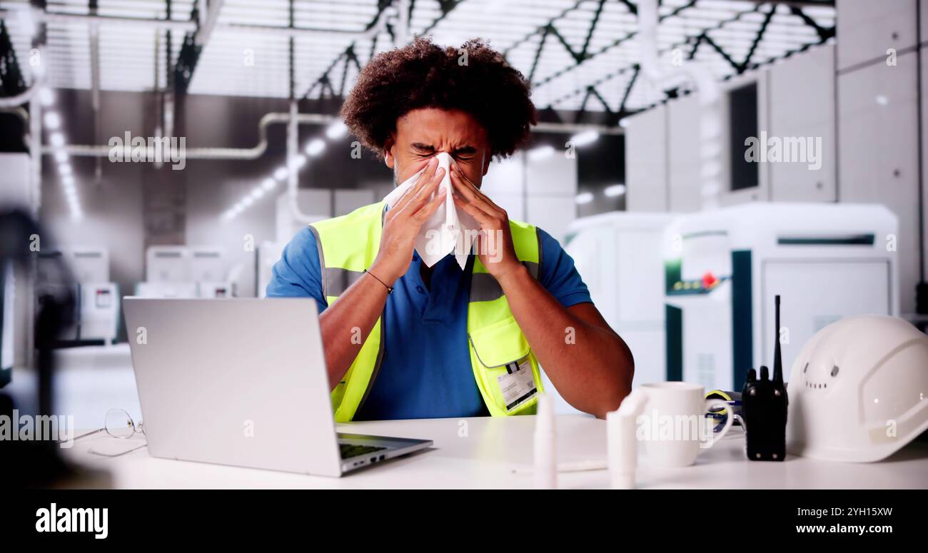Un employé d'usine malade éternue au travail. Grippe ou allergie Banque D'Images