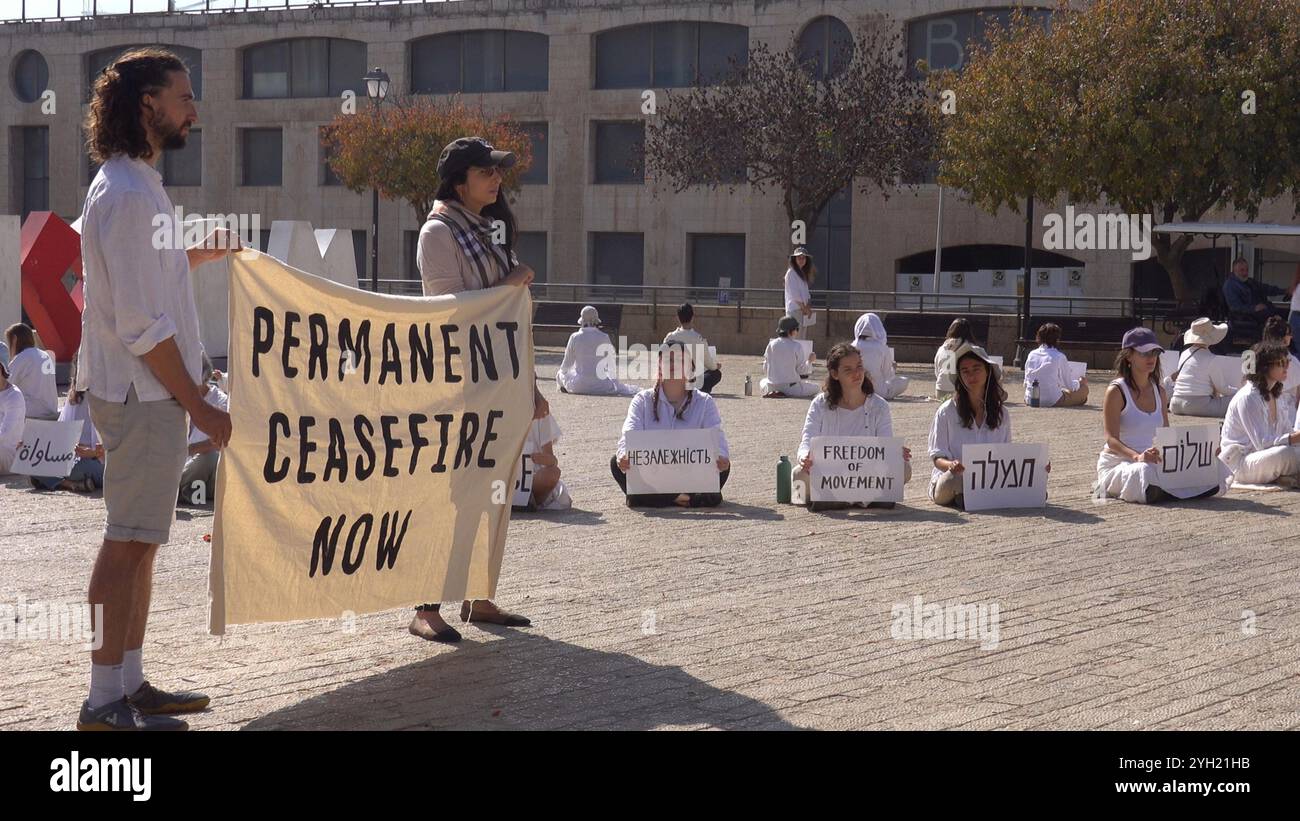 JÉRUSALEM - 8 NOVEMBRE : des militantes israéliennes pour la paix tiennent une banderole portant la mention "cessez-le-feu permanent maintenant" alors que d'autres activistes vêtues de vêtements blancs s'assoient tranquillement en cercle avec des signes promouvant les valeurs de tolérance et de coexistence lors d'une manifestation de sit-in devant la vieille ville appelant à un cessez-le-feu et à une solution diplomatique à la guerre en cours à Gaza et au Liban le 8 novembre 2024 à Jérusalem. Israël Banque D'Images