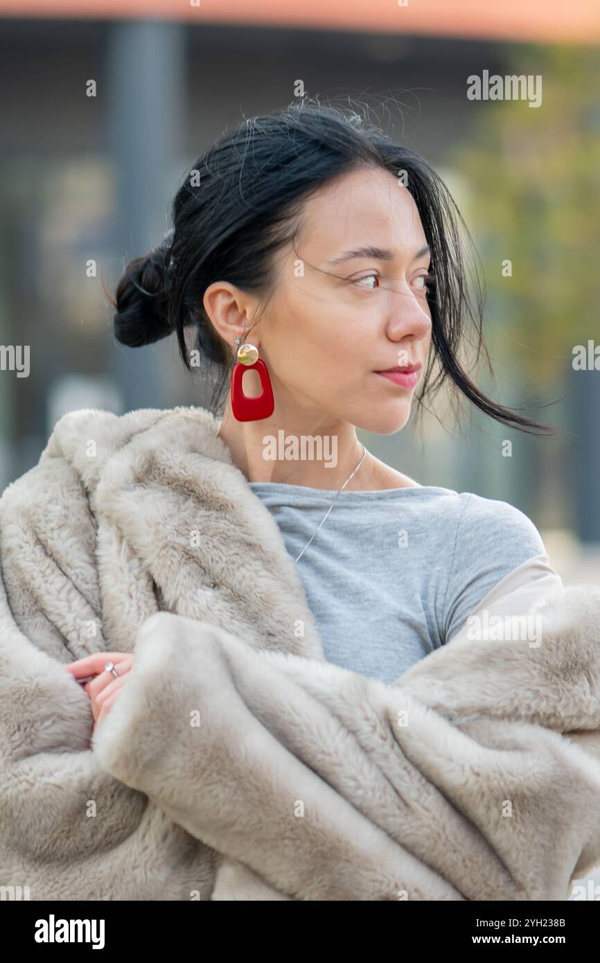 Portrait de rue d'une jeune femme élégante d'apparence orientale, 20-25 ans, sur fond de contours flous d'une ville européenne Banque D'Images
