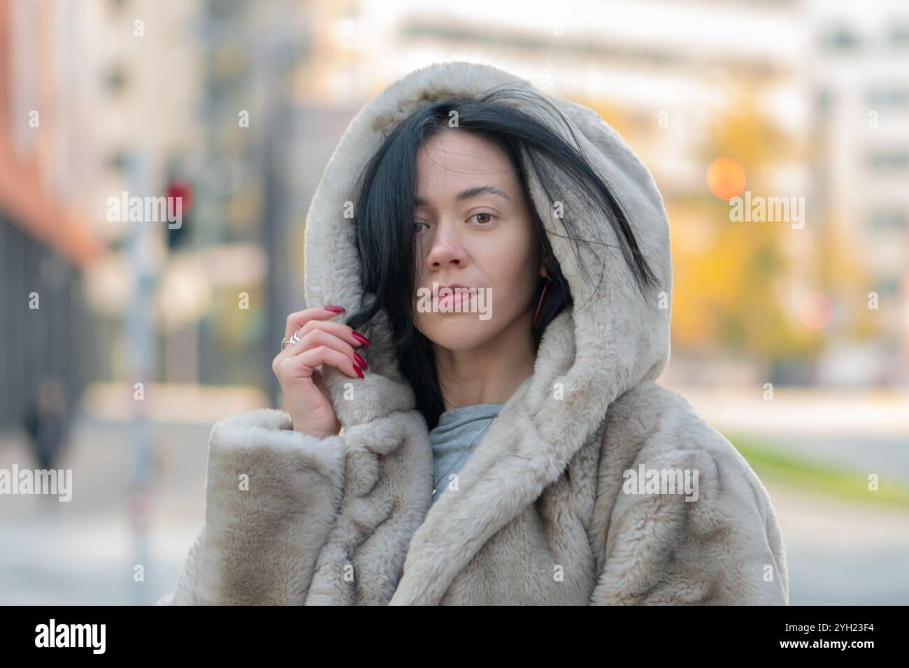 Portrait d'une femme moderne d'apparence orientale, 20-25 ans, sur fond de contours légèrement flous de la métropole. Banque D'Images