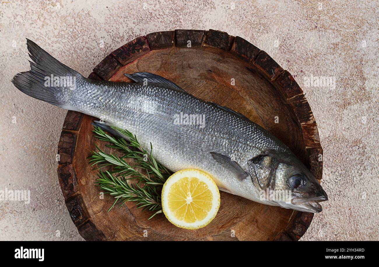 Poisson de bar frais et cru, dans une assiette en bois, vue de dessus, pas de gens Banque D'Images