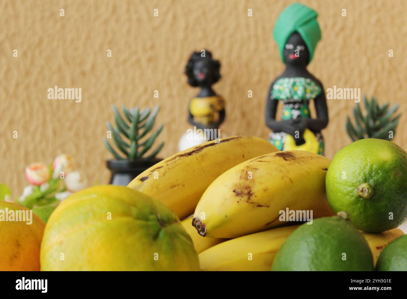 Fruits tropicaux dans la première couche et deux statuettes brésiliennes de femmes noires portant des costumes traditionnels africains dans la couche arrière. Banque D'Images