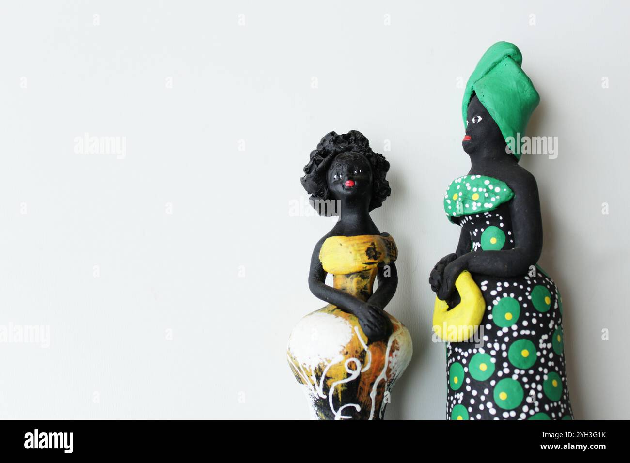 Deux statuettes de femmes noires portant des costumes traditionnels brésiliens verts et jaunes. Fond blanc avec espace de copie. Banque D'Images