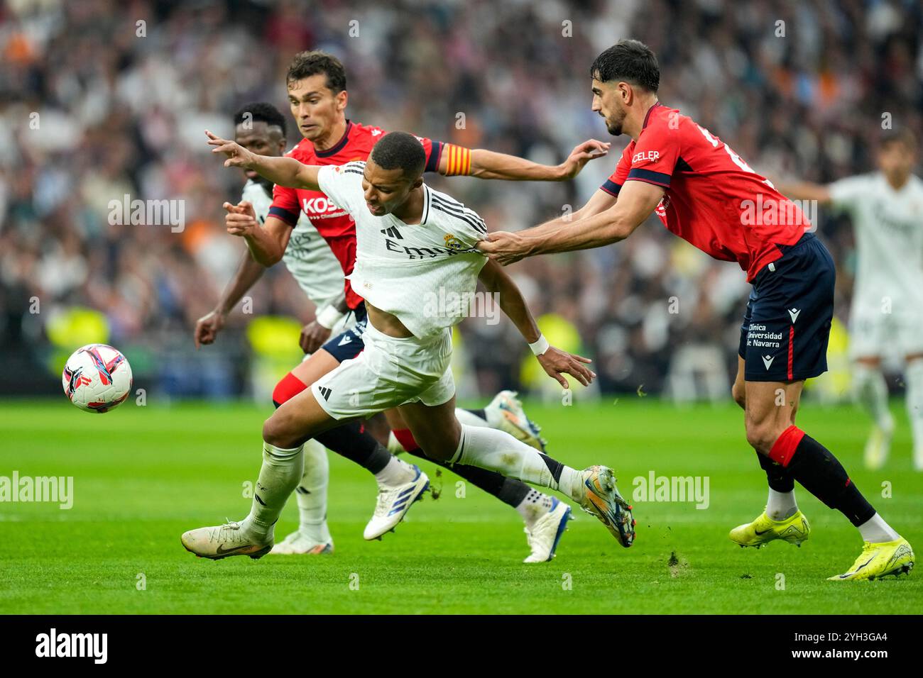 Real Madrid's Kylian Mbappe is challenged by Osasuna's Alejandro Catena, right, during the Spanish La Liga soccer match between Real Madrid and Osasuna at the Santiago Bernabeu stadium in Madrid, Spain, Saturday, Nov. 9, 2024. (AP Photo/Jose Breton) Banque D'Images