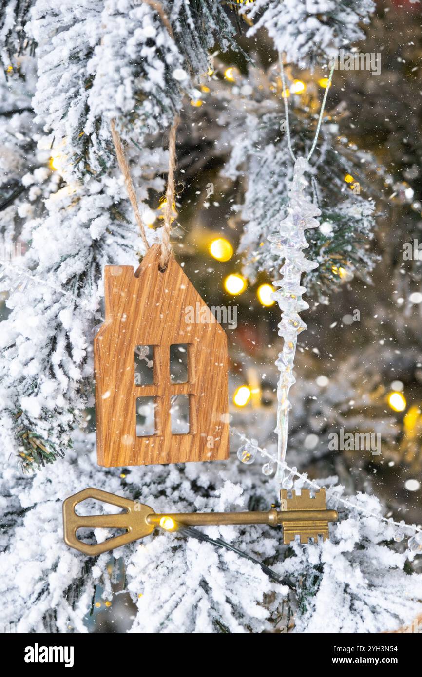 Clé et petit porte-clés maison en main sur fond de lumières de fée arbre de Noël. Cadeau pour le nouvel an, Noël. Construction, conception, projet, déménagement, insura Banque D'Images