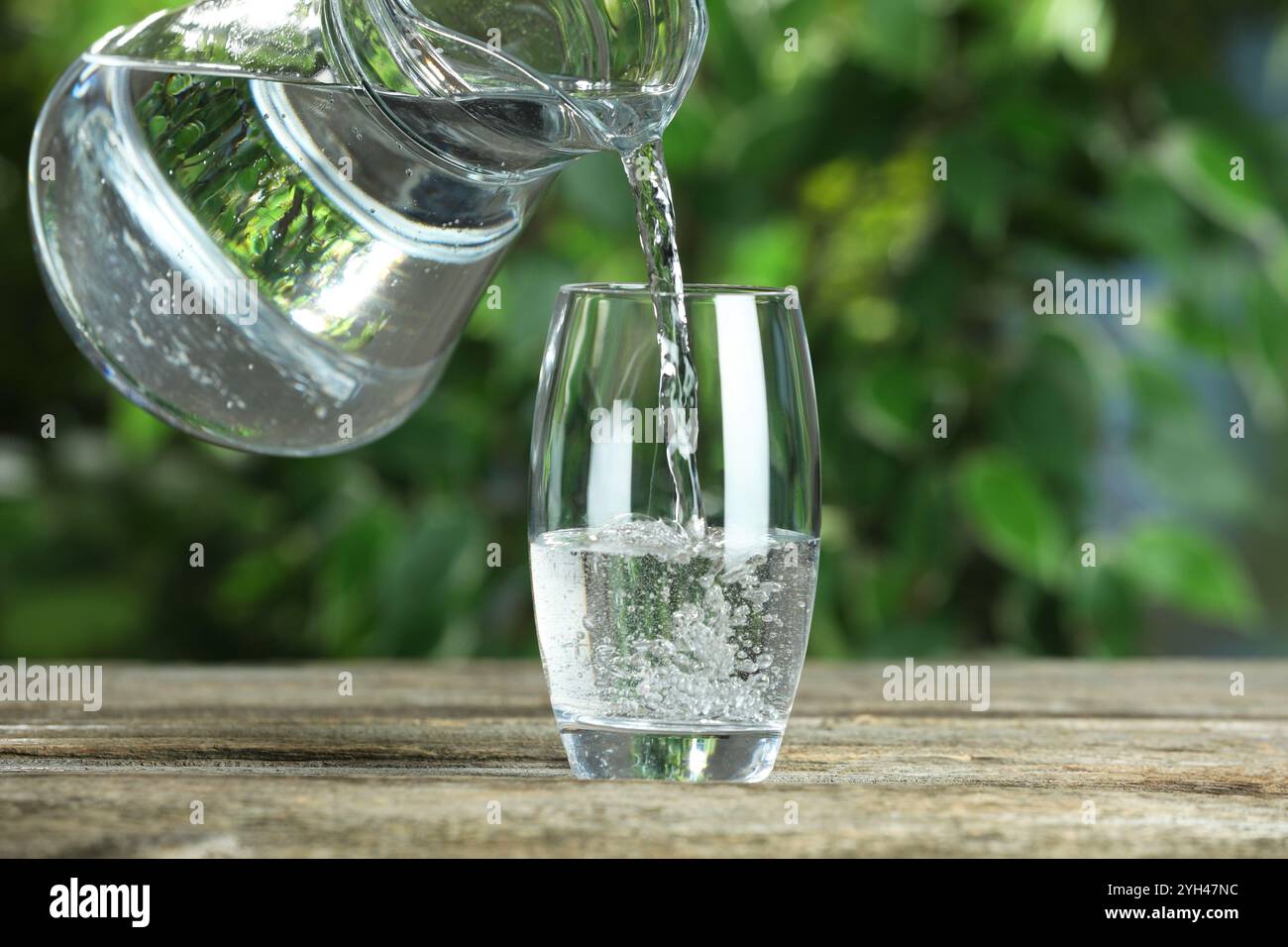Verser de l'eau de soude dans le verre à la table en bois à l'extérieur Banque D'Images