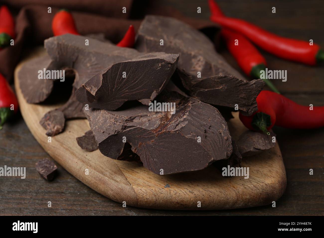 Morceaux de chocolat avec des piments sur une table en bois, gros plan Banque D'Images