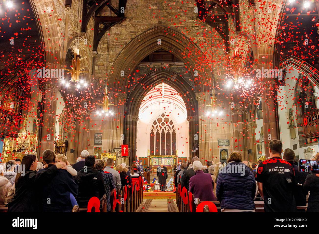 Warrington, Cheshire, Angleterre, Royaume-Uni. 09 novembre 2024. Le festival annuel du souvenir a lieu à l'intérieur de l'église paroissiale St Elphin. Ce fut une soirée pour se souvenir et honorer le service et le sacrifice de nos forces armées dans les conflits mondiaux. Une cascade de coquelicots tombe après le dernier post. Crédit : John Hopkins/Alamy Live News Banque D'Images