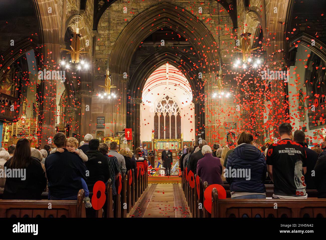 Warrington, Cheshire, Angleterre, Royaume-Uni. 09 novembre 2024. Le festival annuel du souvenir a lieu à l'intérieur de l'église paroissiale St Elphin. Ce fut une soirée pour se souvenir et honorer le service et le sacrifice de nos forces armées dans les conflits mondiaux. Une cascade de coquelicots tombe après le dernier post. Crédit : John Hopkins/Alamy Live News Banque D'Images
