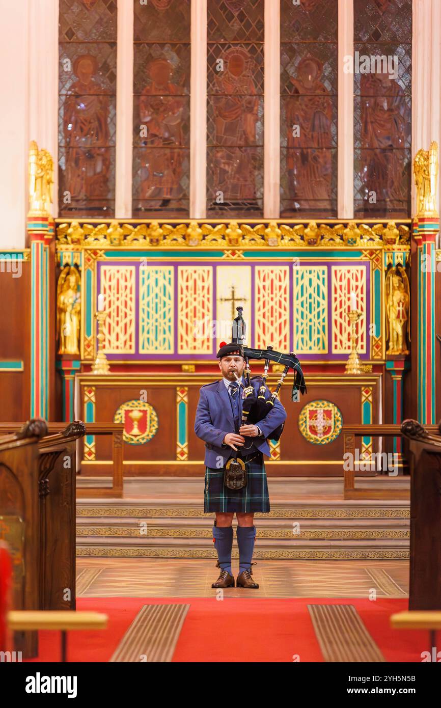 Warrington, Cheshire, Angleterre, Royaume-Uni. 09 novembre 2024. Le festival annuel du souvenir a lieu à l'intérieur de l'église paroissiale St Elphin. Ce fut une soirée pour se souvenir et honorer le service et le sacrifice de nos forces armées dans les conflits mondiaux. Un seul joueur de cornemuse la lamentation des soldats, fleurs de la forêt à l'avant de l'église. Crédit : John Hopkins/Alamy Live News Banque D'Images
