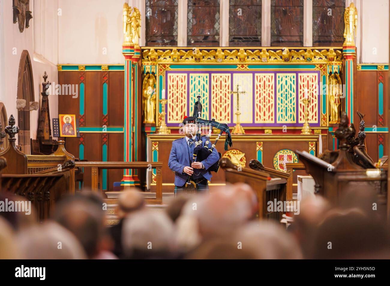 Warrington, Cheshire, Angleterre, Royaume-Uni. 09 novembre 2024. Le festival annuel du souvenir a lieu à l'intérieur de l'église paroissiale St Elphin. Ce fut une soirée pour se souvenir et honorer le service et le sacrifice de nos forces armées dans les conflits mondiaux. Un seul joueur de cornemuse la lamentation des soldats, fleurs de la forêt à l'avant de l'église. Crédit : John Hopkins/Alamy Live News Banque D'Images