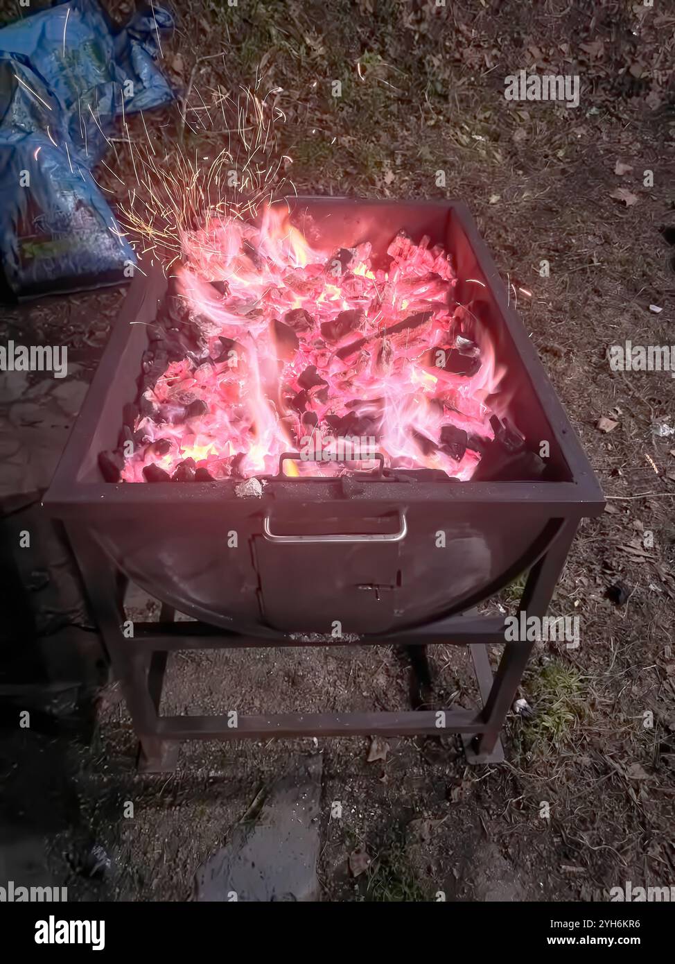 Braises incandescentes et charbons chauds préparés pour un barbecue en plein air. La chaleur intense et les étincelles créent une atmosphère rustique et accueillante pour griller. Banque D'Images
