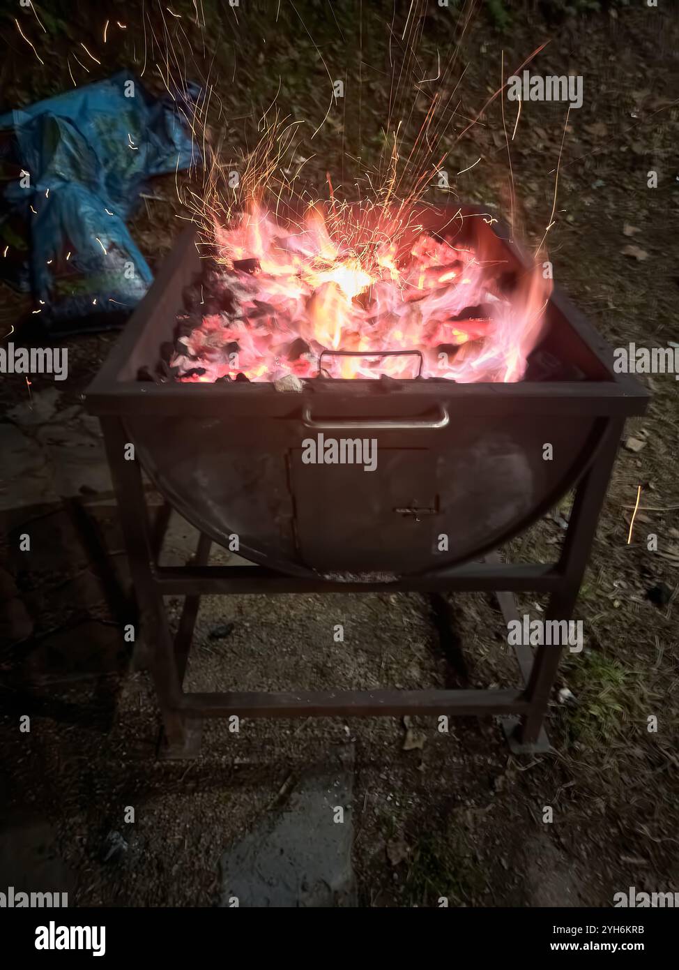 Braises incandescentes et charbons chauds préparés pour un barbecue en plein air. La chaleur intense et les étincelles créent une atmosphère rustique et accueillante pour griller. Banque D'Images