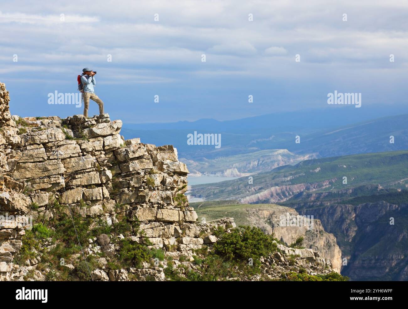 Une jeune femme photographe debout sur le bord d'une falaise prend des photos d'un magnifique paysage de montagne Banque D'Images