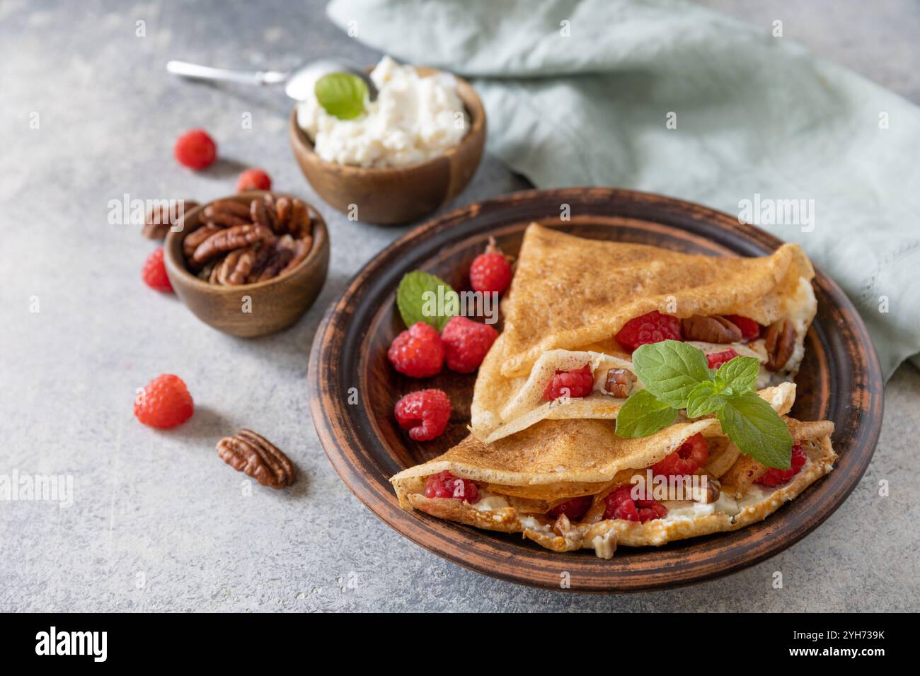 Savoureuses crêpes sucrées maison farcies aux framboises et au fromage à la crème sur un fond de pierre grise. Crêpes fines, blini. Dessert sucré. Banque D'Images