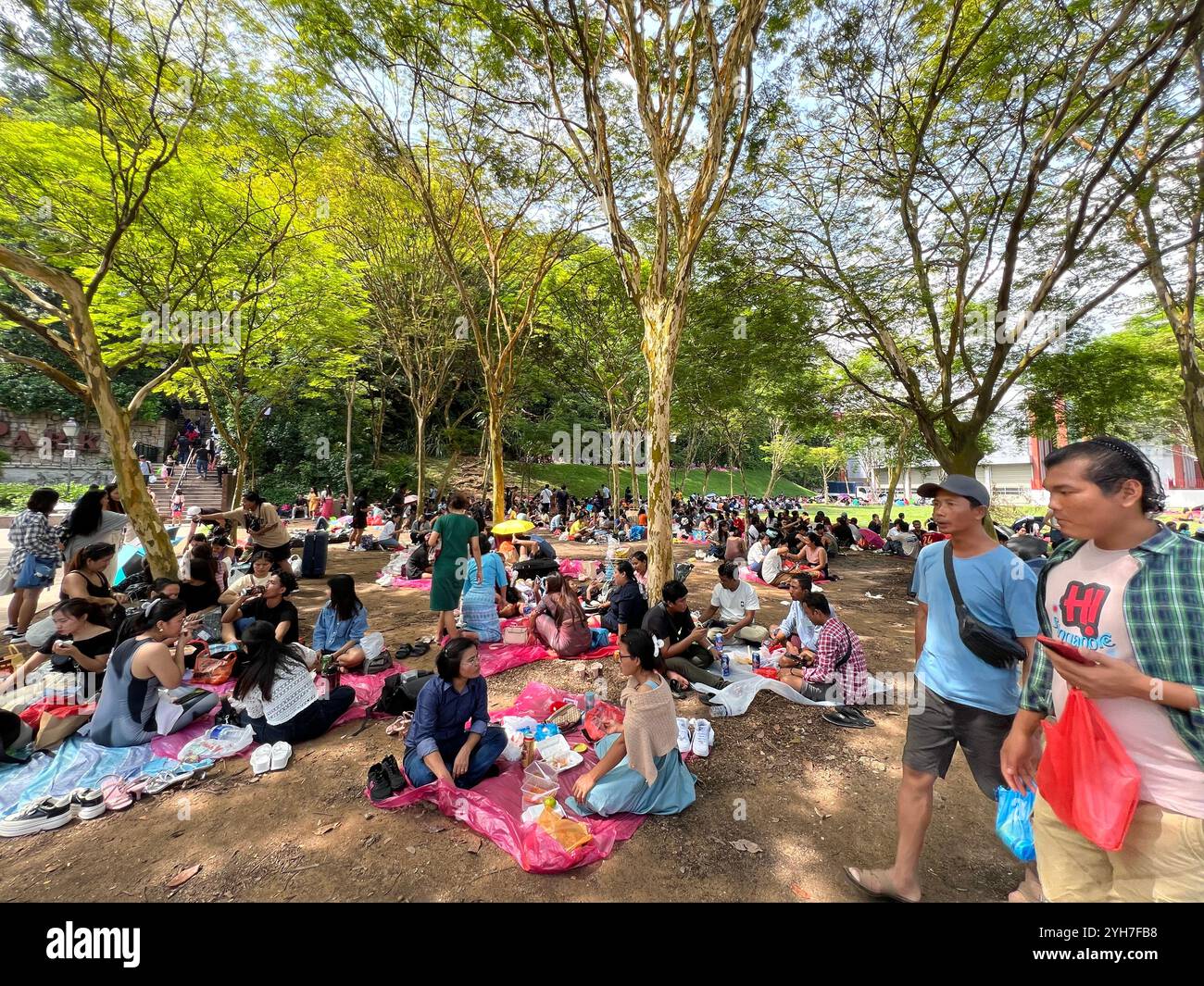 Groupe différent de travailleurs étrangers ayant pique-nique et se détendre dans un espace ouvert. Simplement bavarder, manger et boire. Entrée de Fort Canning Park, Singapour Banque D'Images