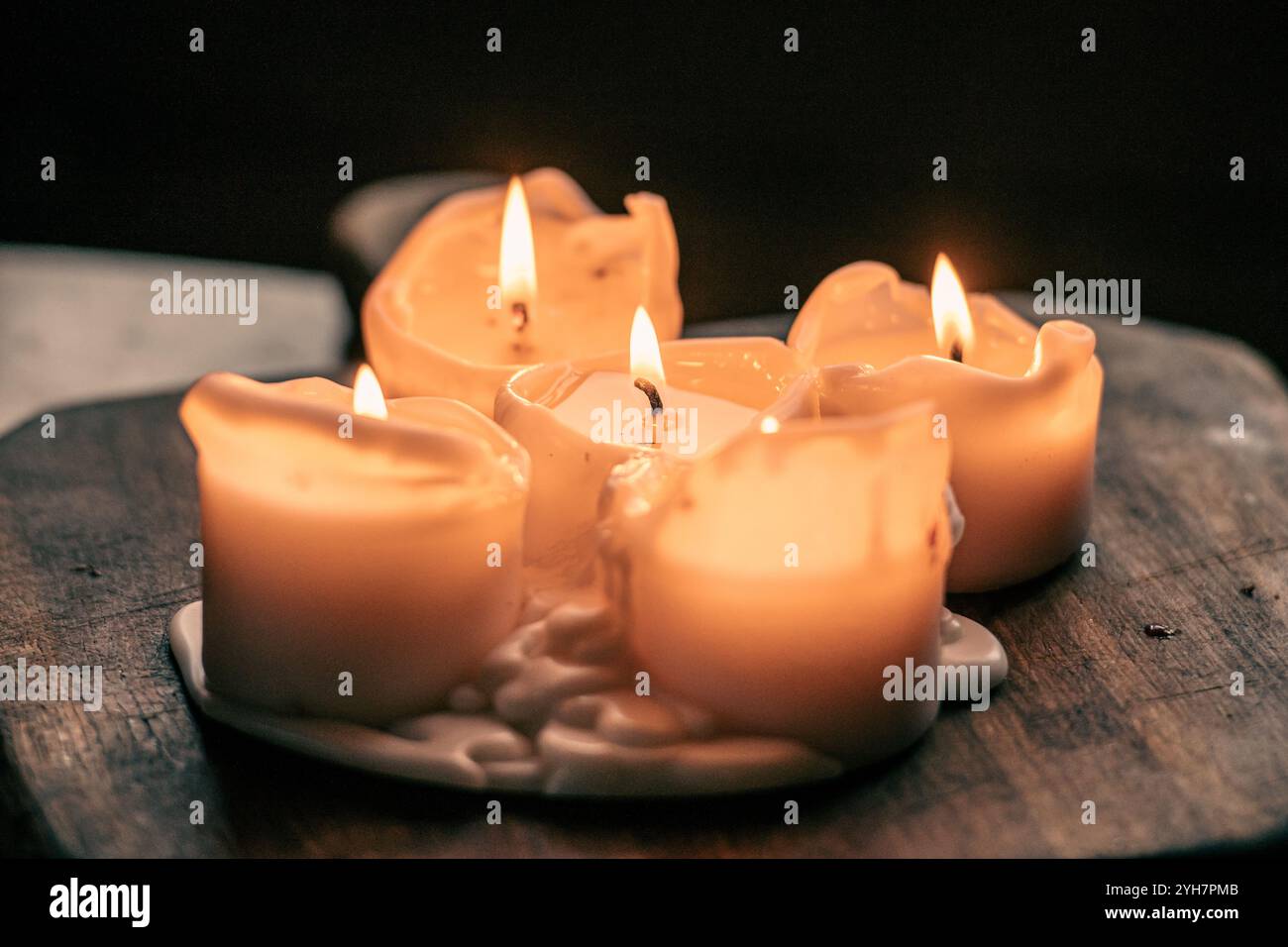 Bougies de cire brûlant sur une planche ou une table en bois, atmosphère chaleureuse, fond chaud et sombre, gros plan Banque D'Images