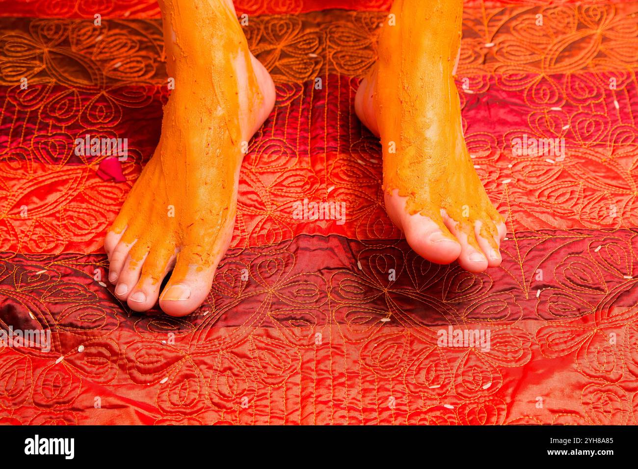 Cérémonie traditionnelle de mariage indien Haldi - pâte jaune appliquée sur les pieds du marié pour les bénédictions Banque D'Images