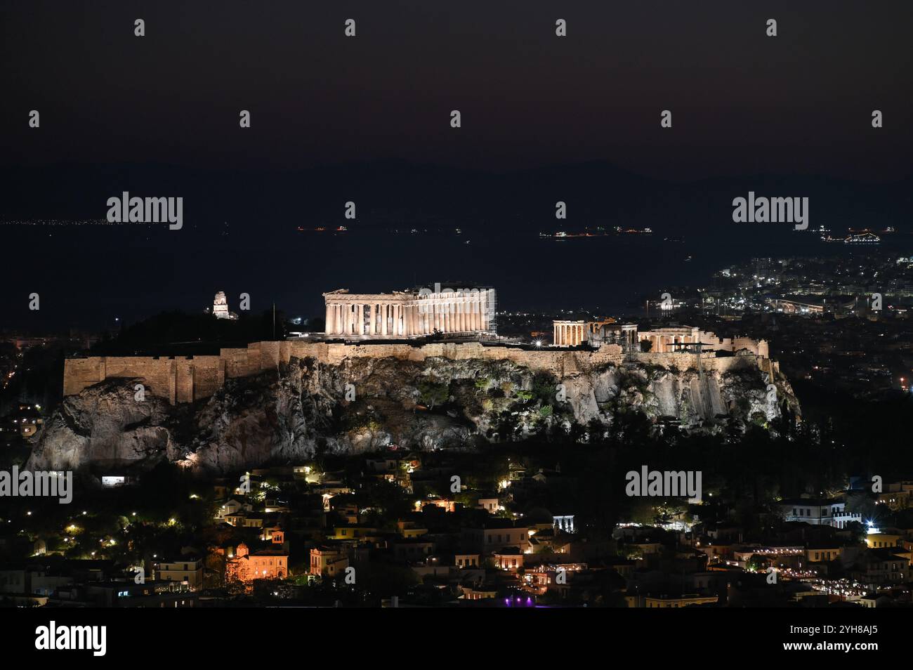 Une vue sur la ville d'Athènes et la colline de l'Acropole avec le temple du Parthénon illuminé après le coucher du soleil au-dessus du golfe Saronique. Athènes, Grèce Banque D'Images